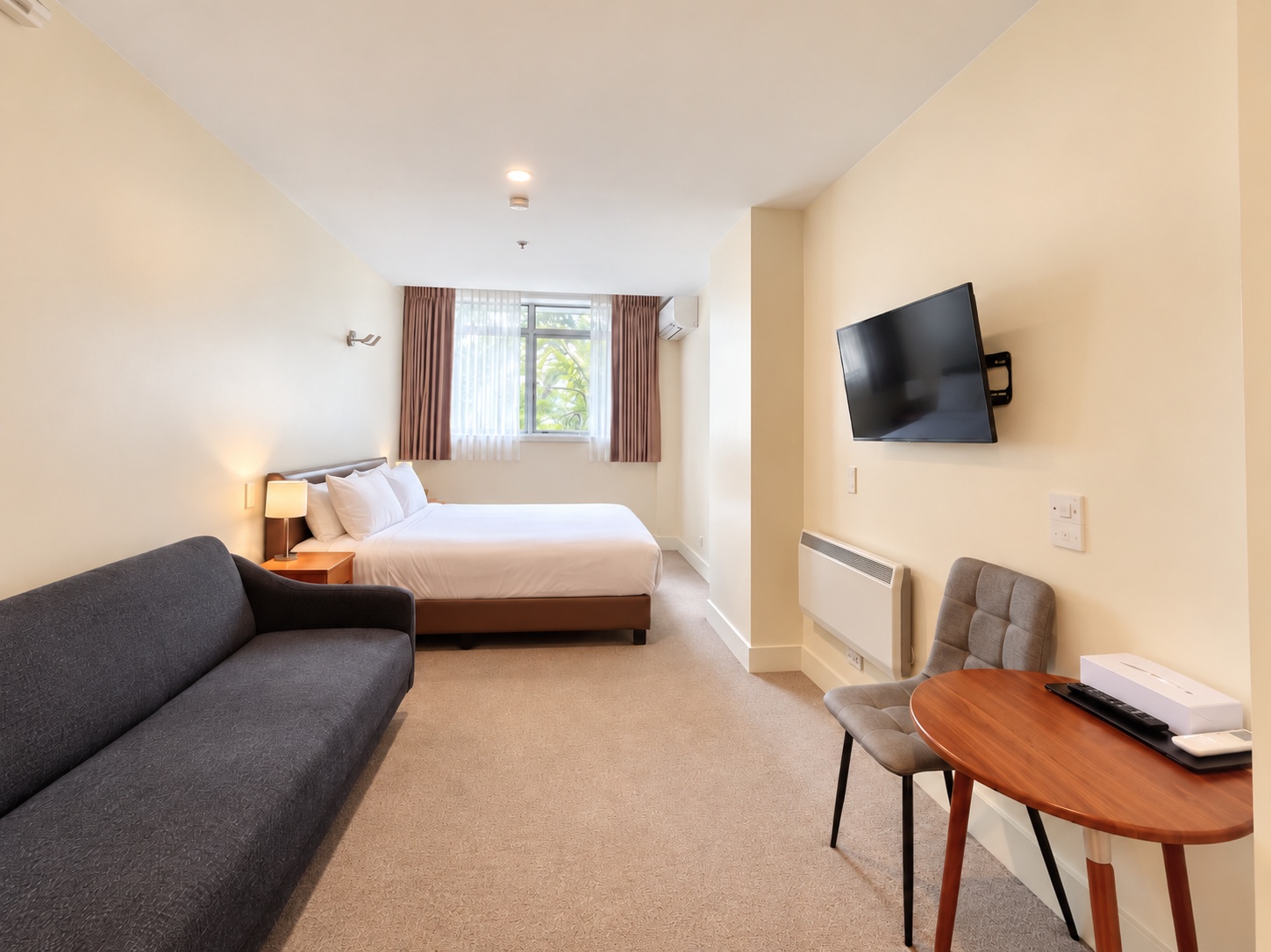 Deluxe King full-room view with king bed, sofa and dining table.